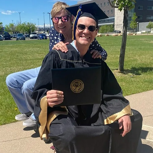 Pamela A. Walton posing with a college graduate holding up his degree